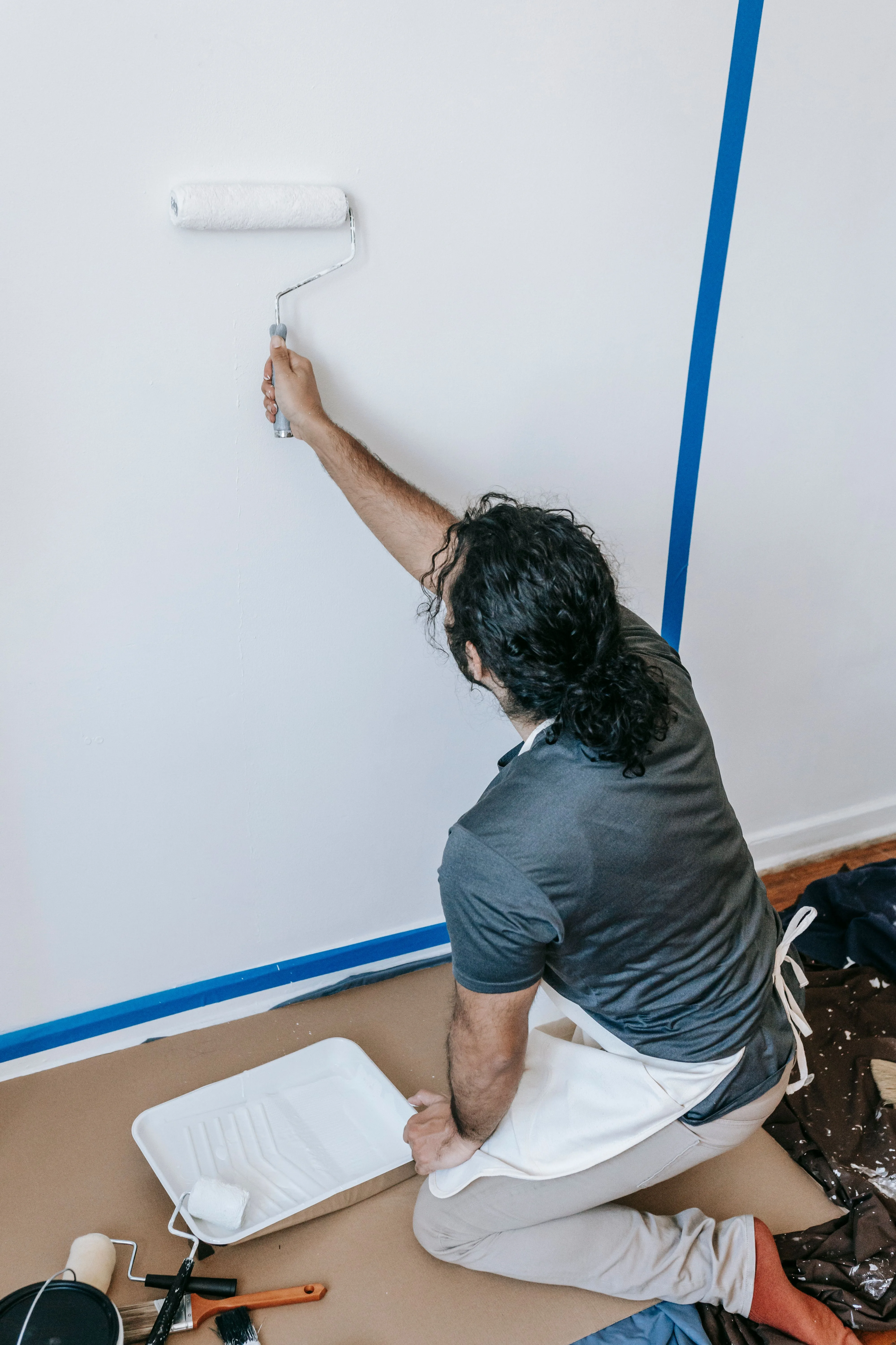 Man using a paint roller to apply fresh paint to a wall during a room renovation