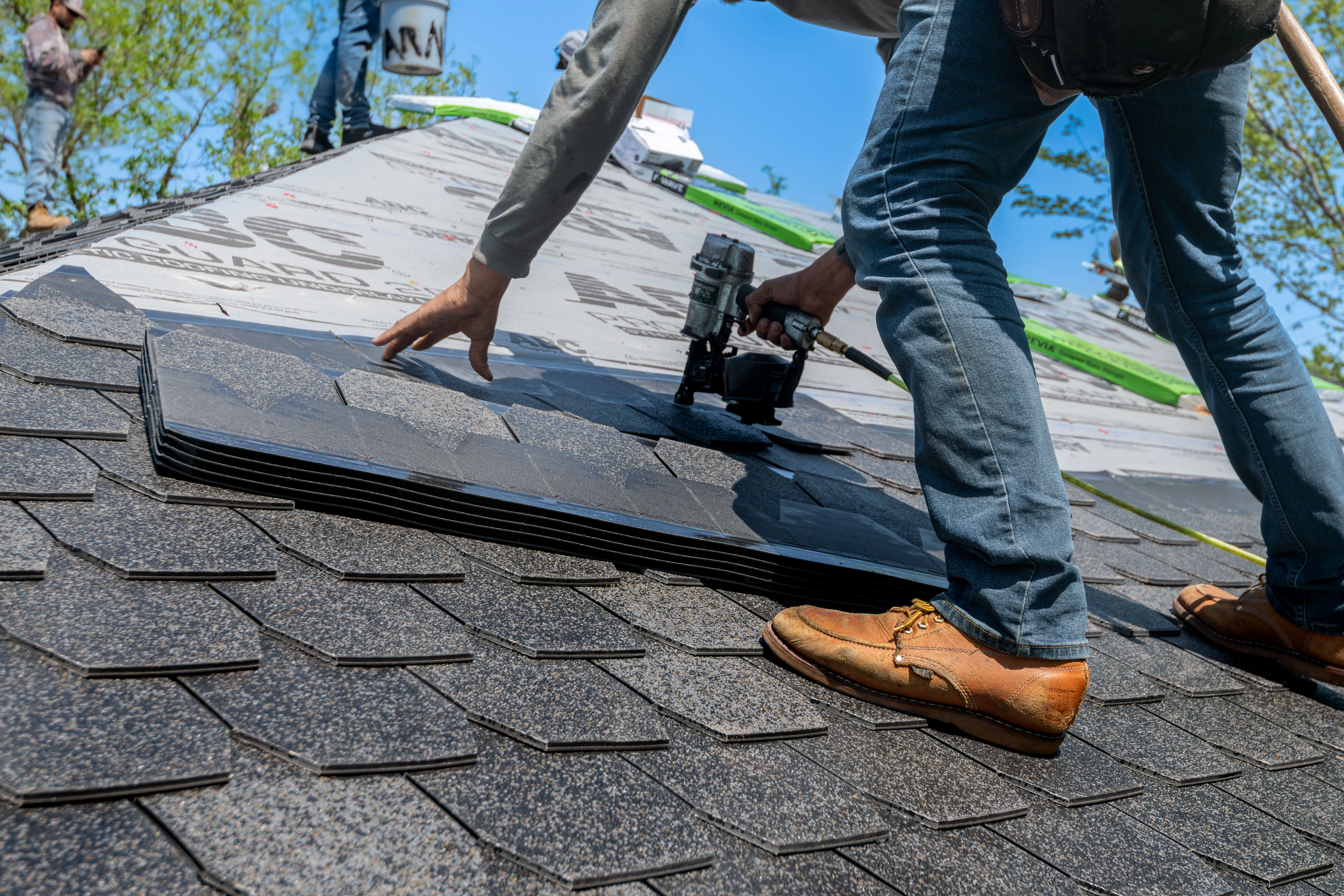 Professional roofer installing new asphalt shingles on a residential roof.