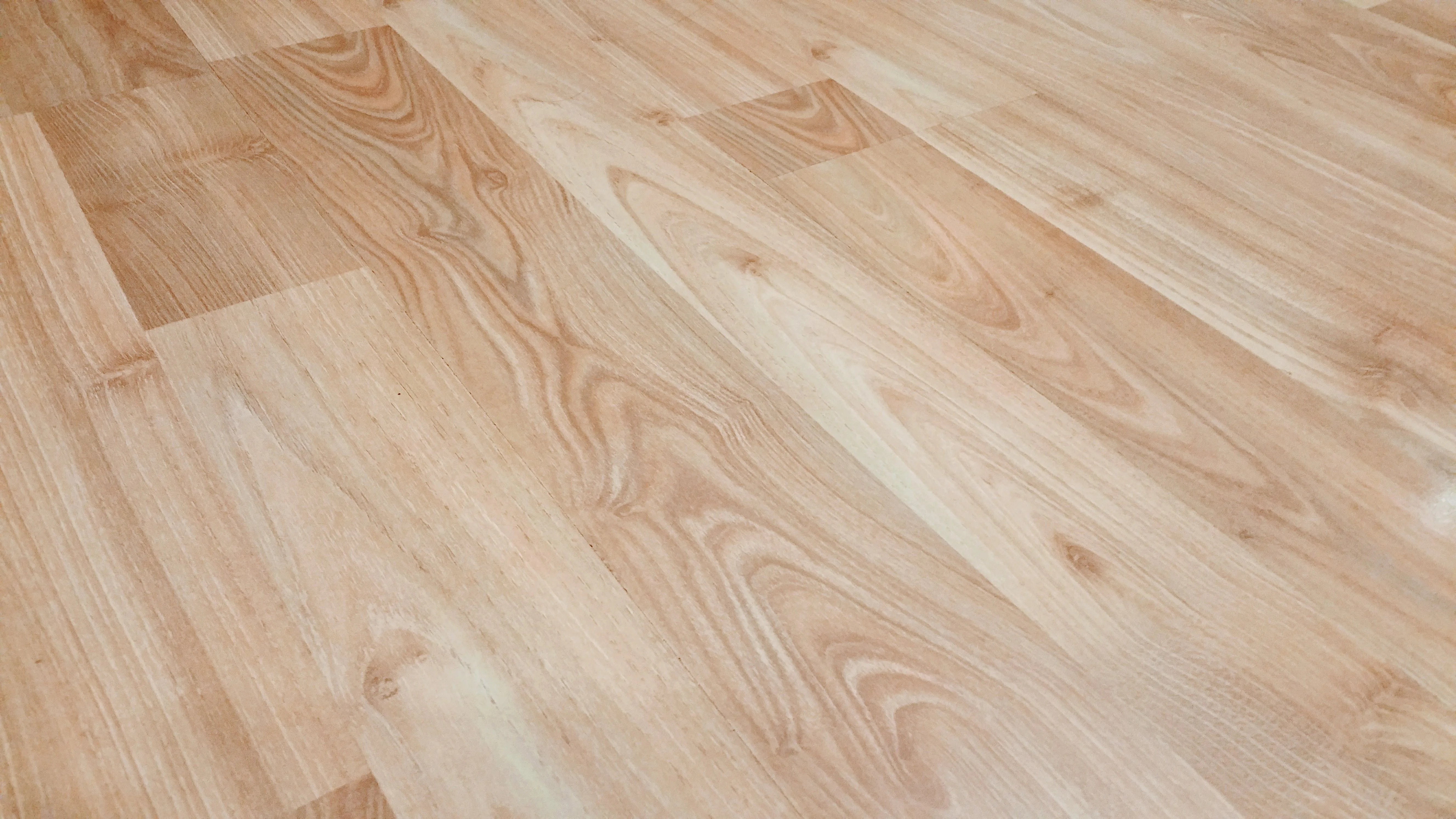 Close-up of smooth light brown wood-look plank flooring, representative of a finished vinyl plank floor.